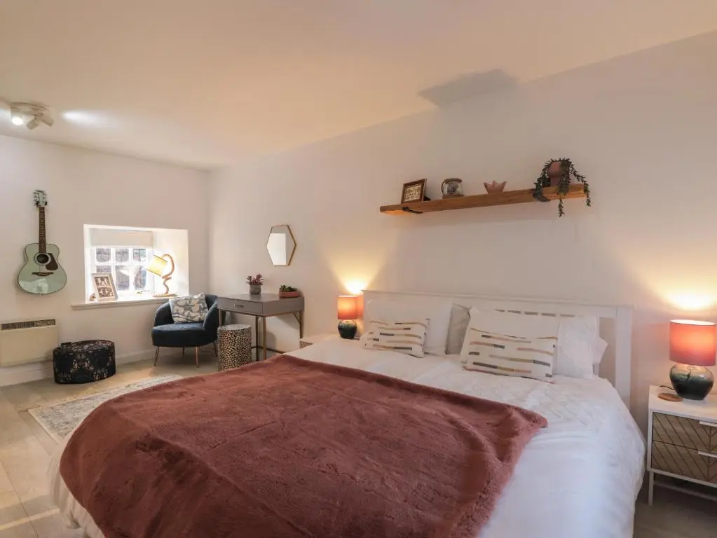 a bedroom with a large bed and a desk at Flat 4, The Byre in Cromarty