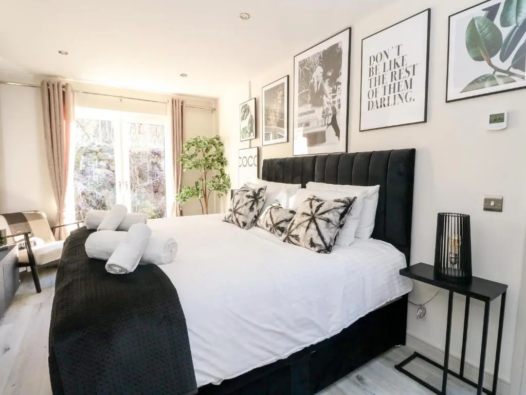 a bedroom with a large bed with white sheets and pillows at Heilan Roo in Pitlochry