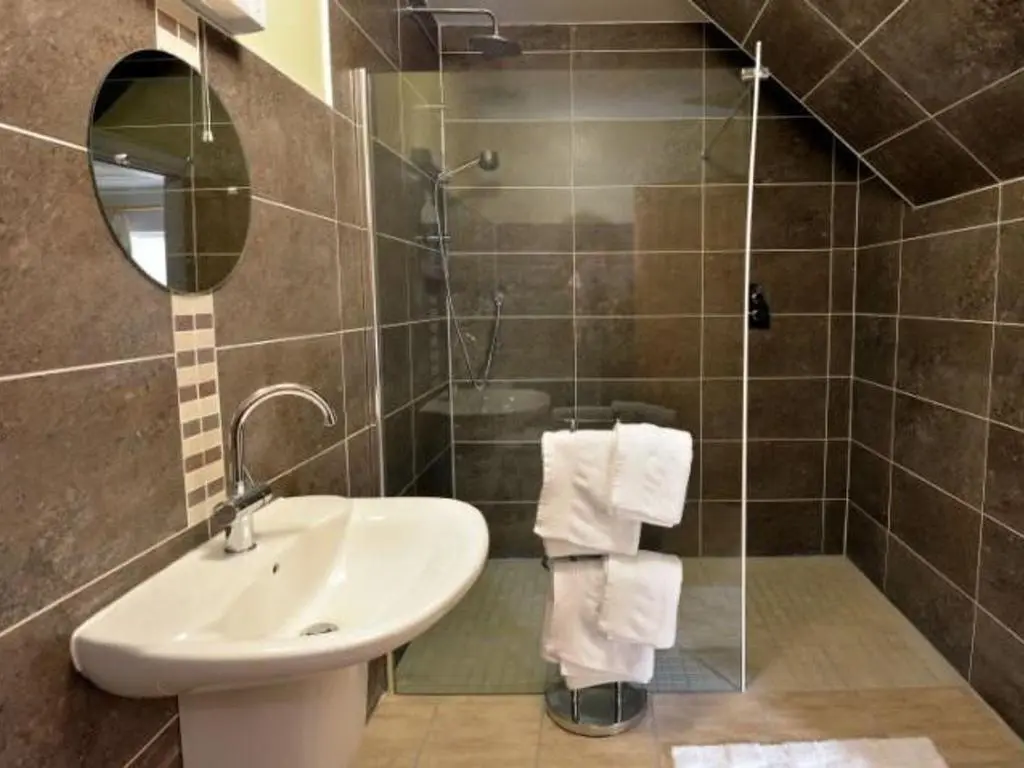 a bathroom with a sink and a shower with a mirror at Glen View Lodge in Inverness
