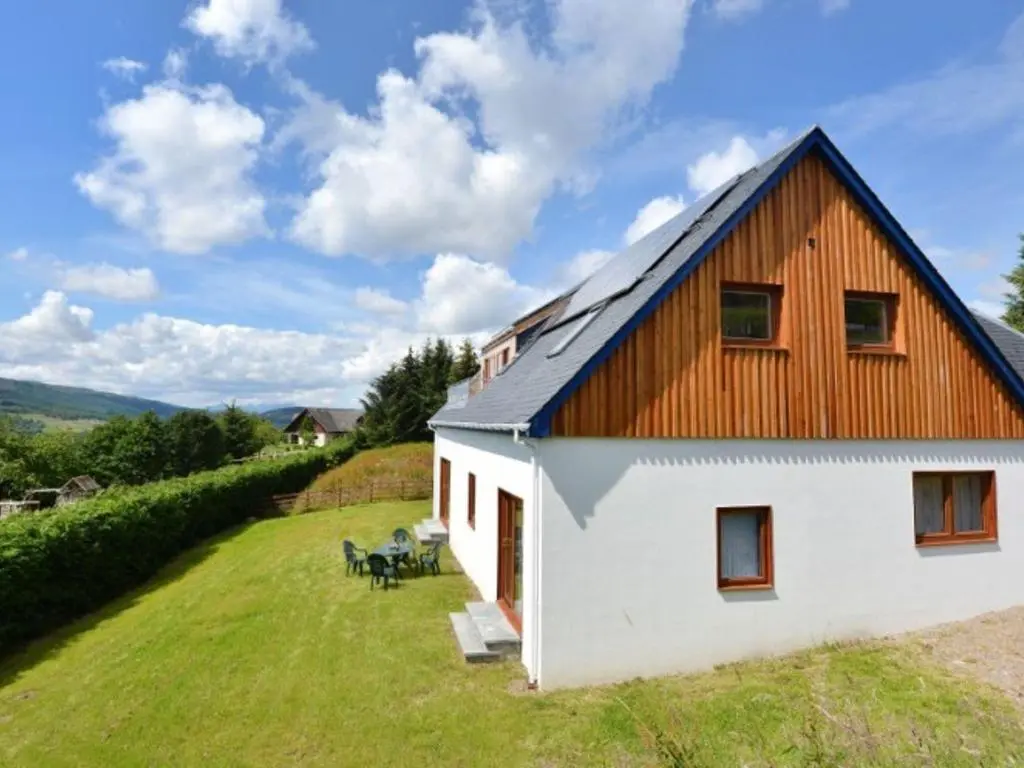a large white house with a wooden roof at Glen View Lodge in Inverness