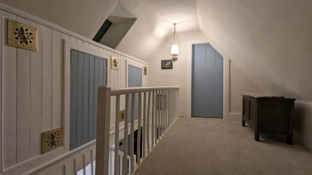 a hallway with a stairway with a door and a stair at Historic character cottage in central Dornoch in Dornoch
