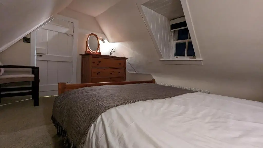 a bedroom with a bed and a dresser and a window at Historic character cottage in central Dornoch in Dornoch