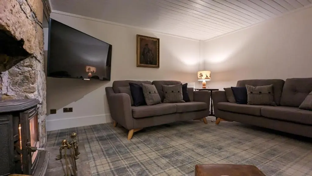 a living room with two couches and a flat screen tv at Historic character cottage in central Dornoch in Dornoch