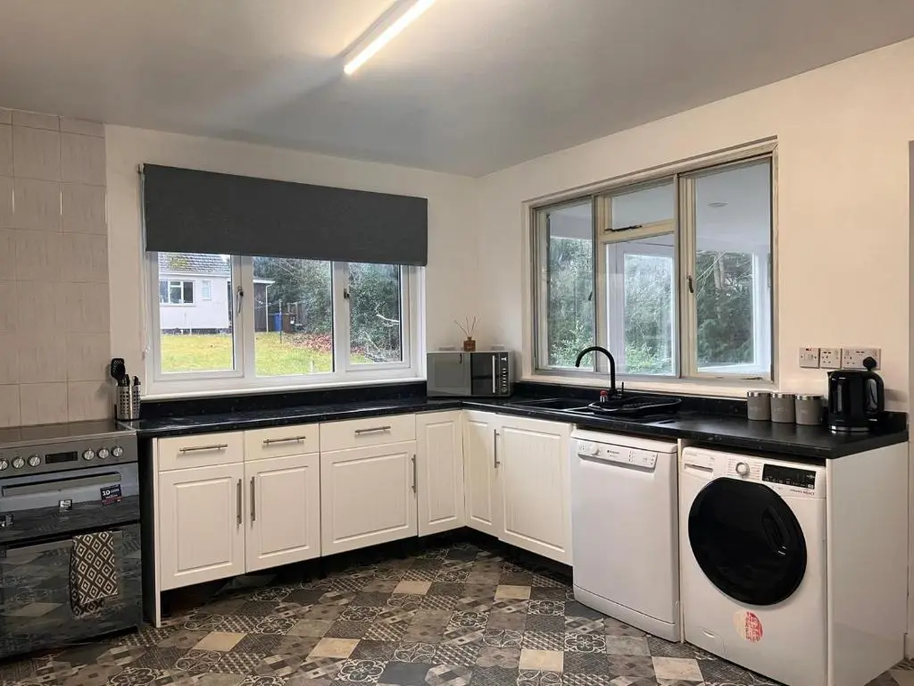 a kitchen with white cabinets and a sink and windows at Shared House in Inverness in Inverness