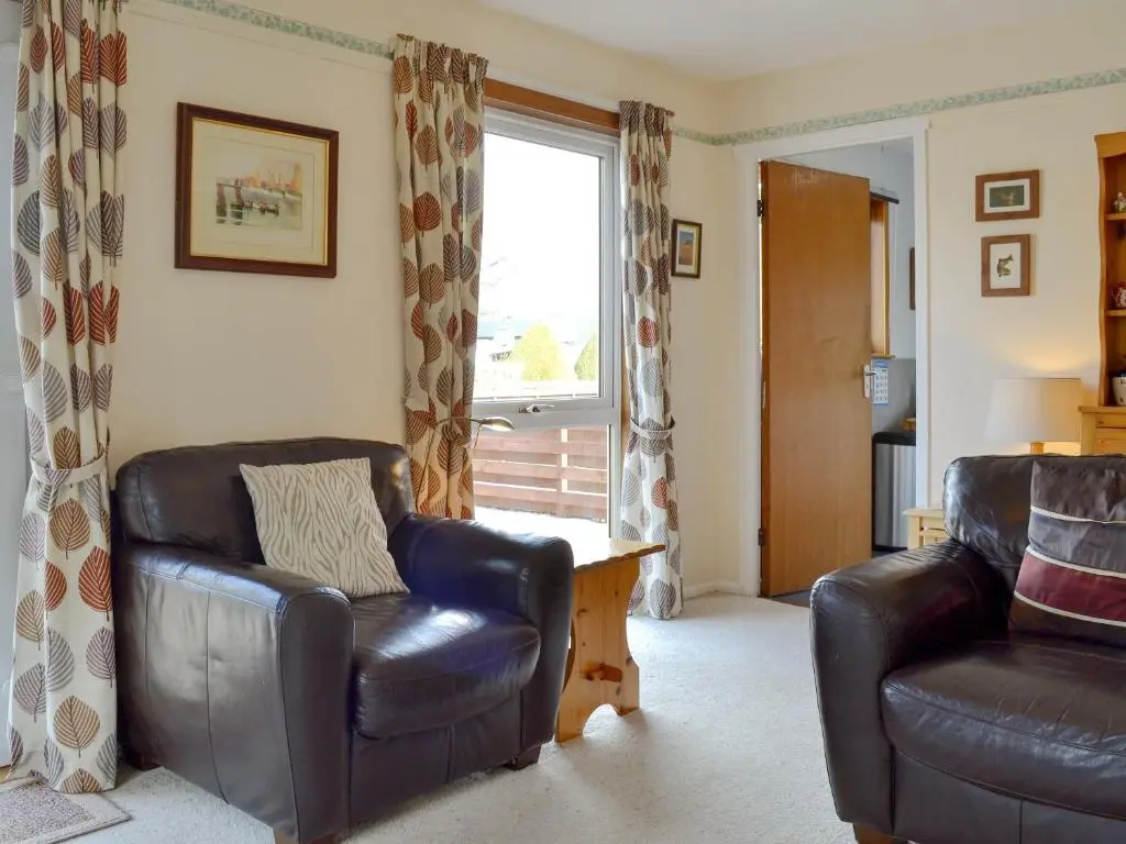 a living room with two leather chairs and a window at Cedar Cottage - Uk32633 in Grantown on Spey