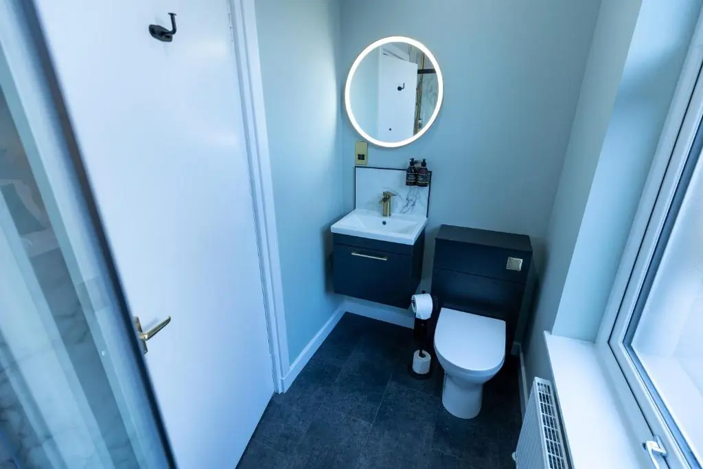 a blue bathroom with a toilet and a mirror at The Crossing in Kingussie