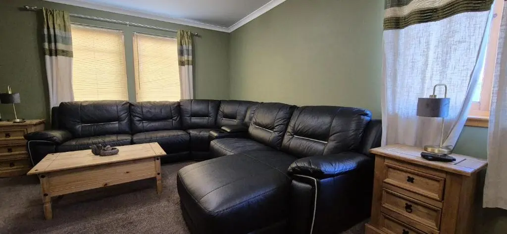a living room with a leather couch and a table at Mountain View No12 in Aviemore