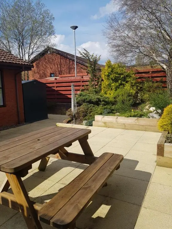 a wooden picnic table sitting on a patio at Orange Squirrel Lodge in Aviemore