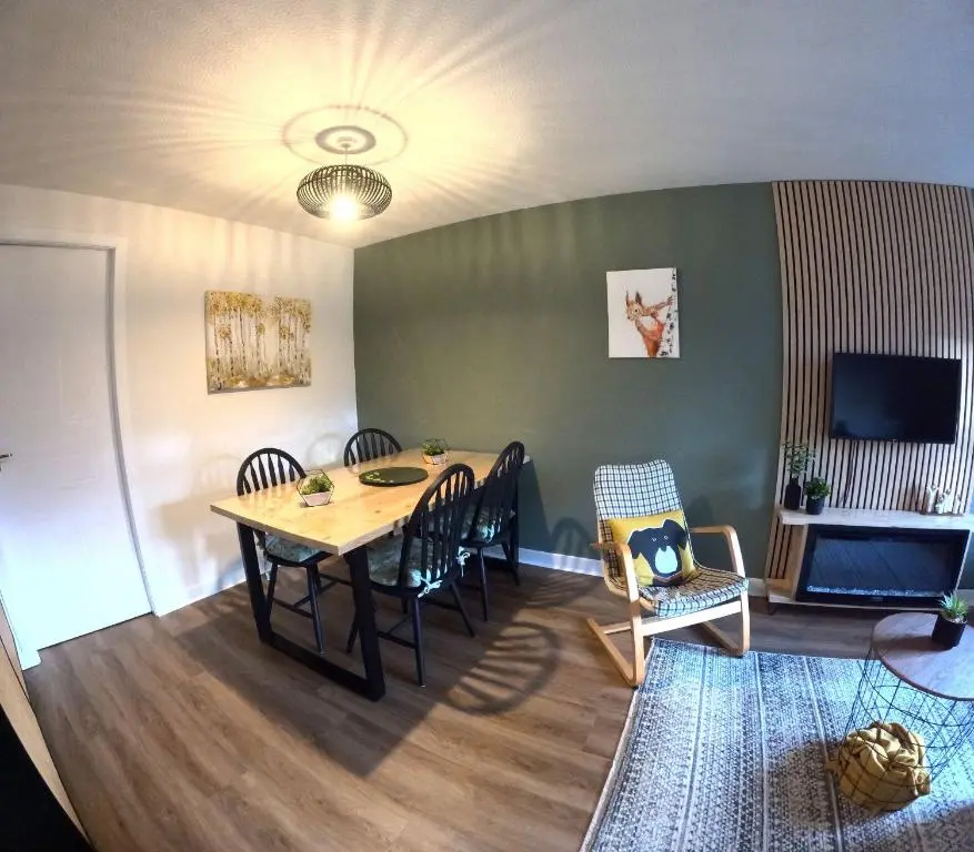 a dining room with a table and chairs and a television at Orange Squirrel Lodge in Aviemore