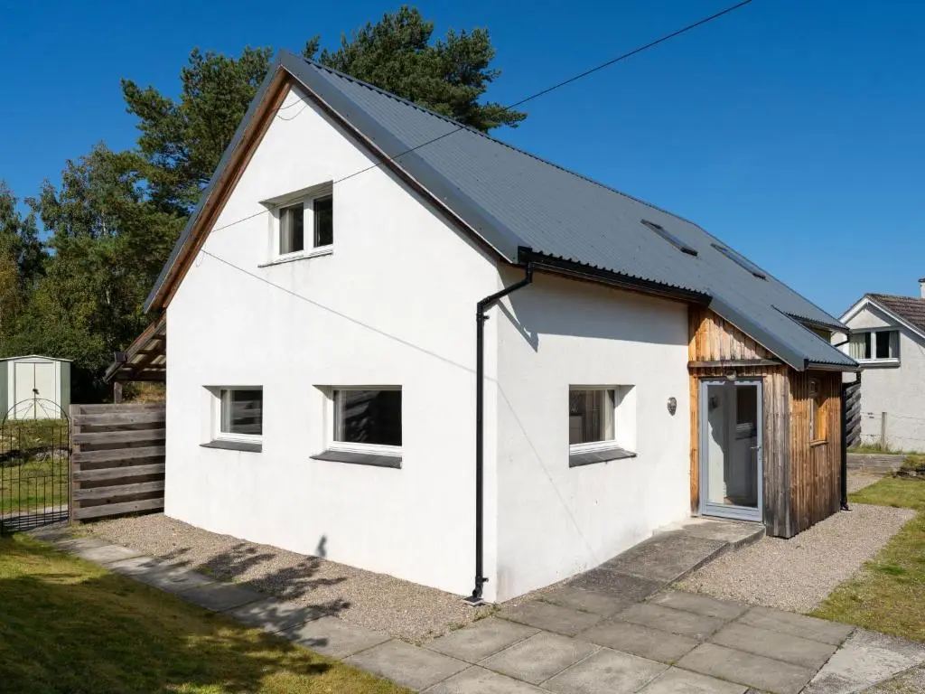 a white house with a black roof at Holiday Home Muir Edge by Interhome in Nethy Bridge