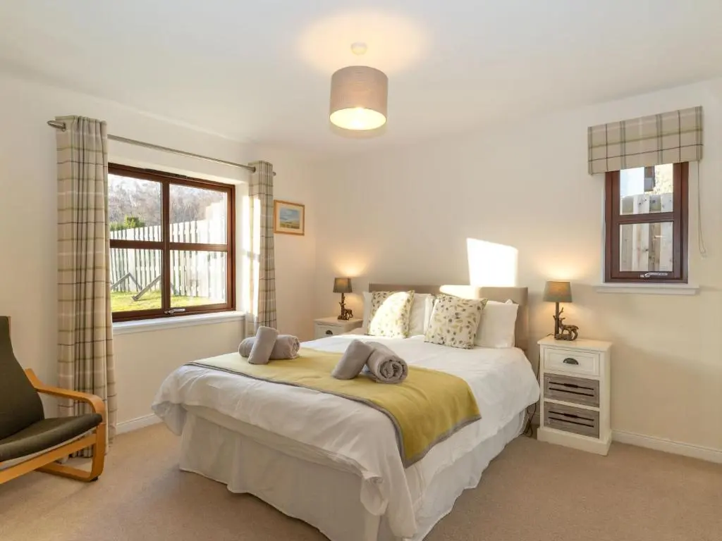 a bedroom with a bed and a chair and a window at Villa Pineways by Interhome in Aviemore