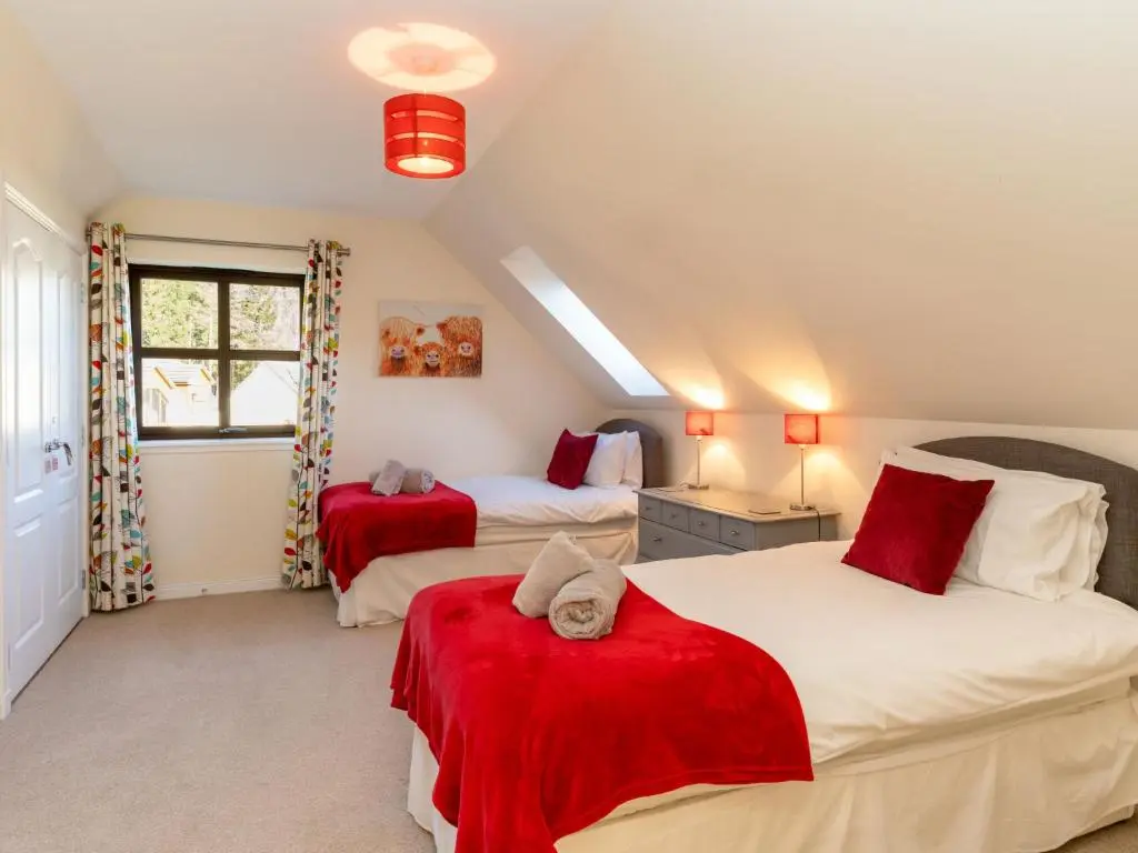 a bedroom with two beds with red sheets at Villa Pineways by Interhome in Aviemore