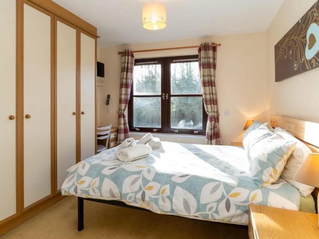a bedroom with a bed and a window at Holiday Home Glenfiddich by Interhome in Aviemore
