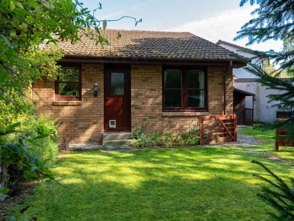 a brick house with a red door and a yard at Holiday Home Glenfiddich by Interhome in Aviemore