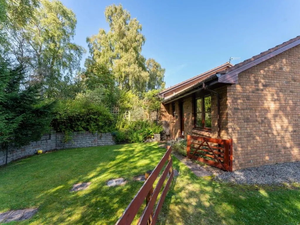 a house with a fence in front of a yard at Holiday Home Glenfiddich by Interhome in Aviemore
