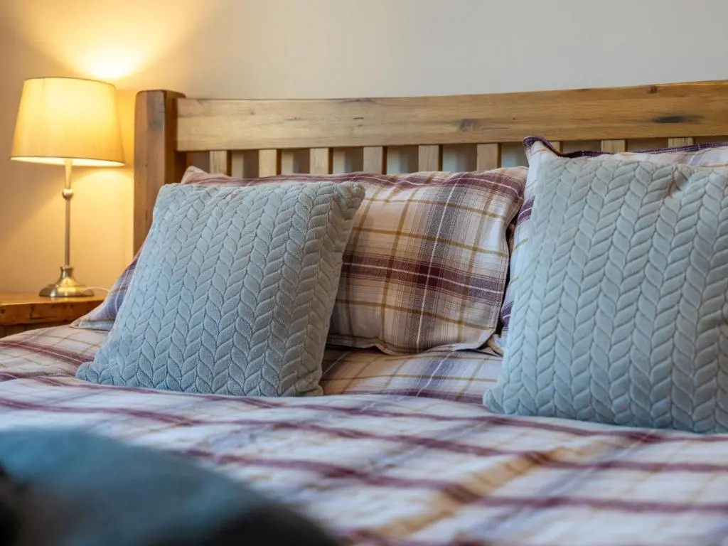 a bed with two pillows and a plaid blanket at Apartment The Bruach by Interhome in Aviemore