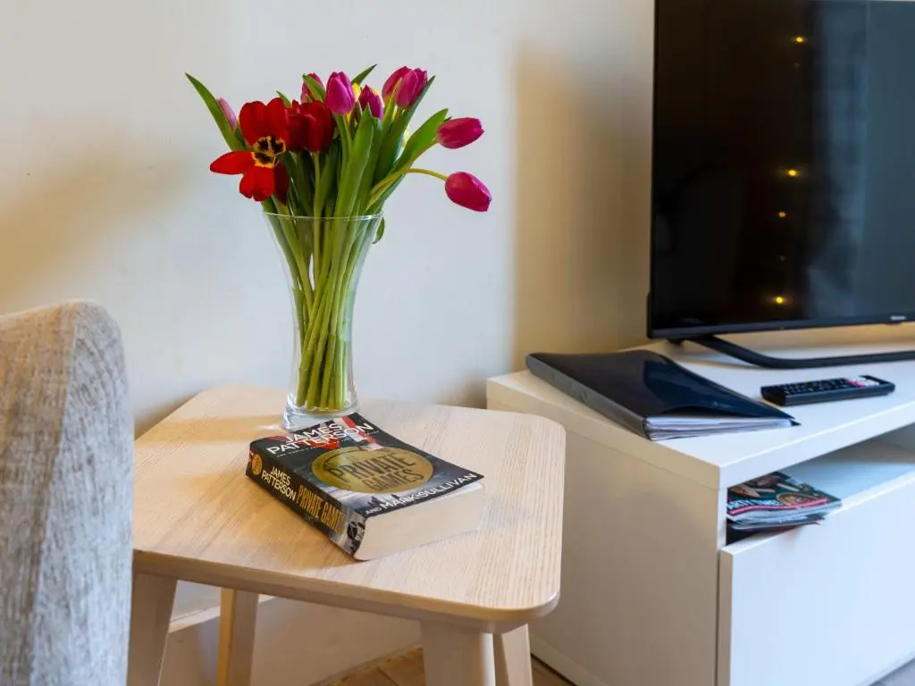 a vase of flowers sitting on a table with a book at Holiday Home 1 Railway Cottage by Interhome in Aviemore
