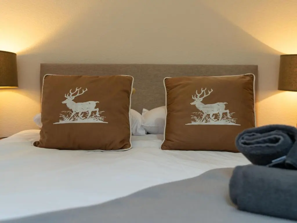 a bed with two pillows with deer prints on them at Holiday Home 1 Railway Cottage by Interhome in Aviemore