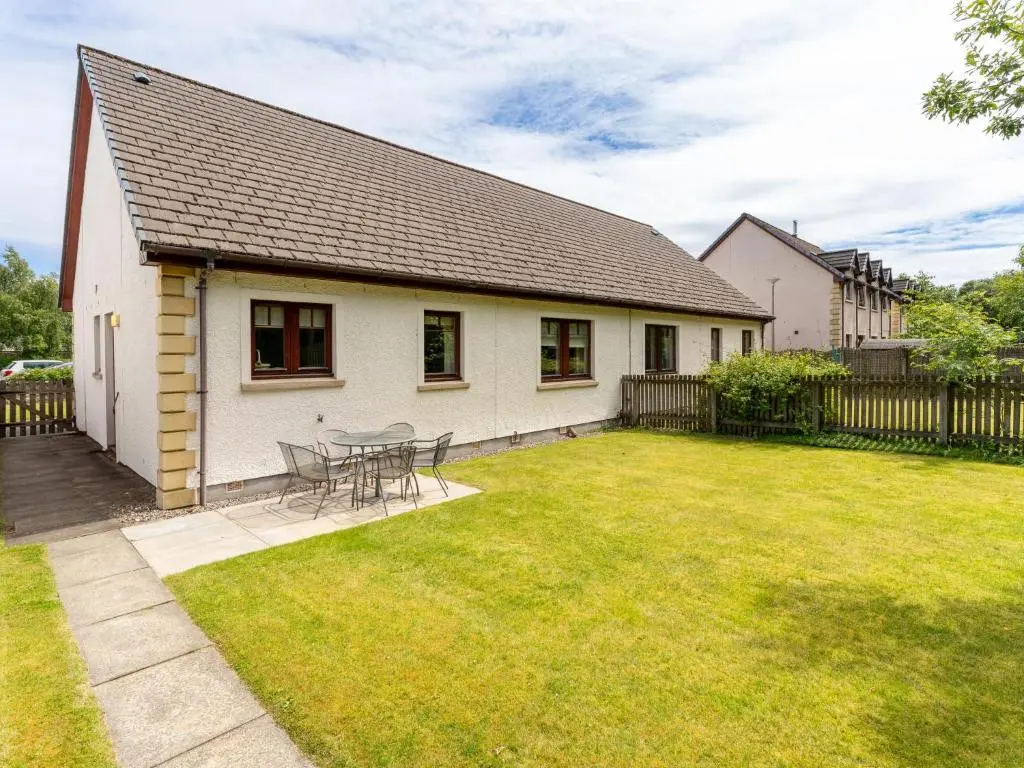 a white house with a table and chairs in a yard at Holiday Home Culduthel by Interhome in Aviemore