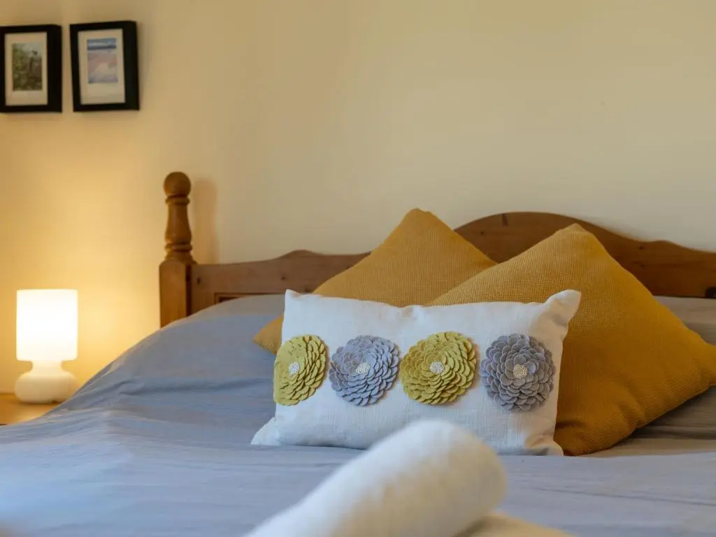 a bed with blue and yellow pillows on it at Holiday Home Culduthel by Interhome in Aviemore