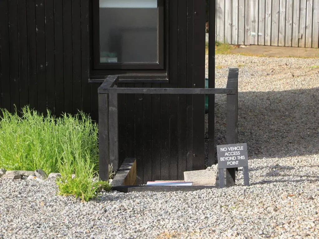 a sign in front of a black house with a no waste sign in front at Core-na-bye in Inverness