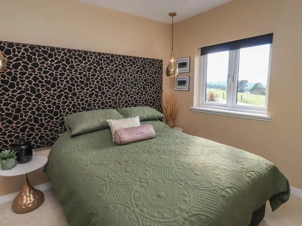 a bedroom with a green bed and a window at Core-na-bye in Inverness