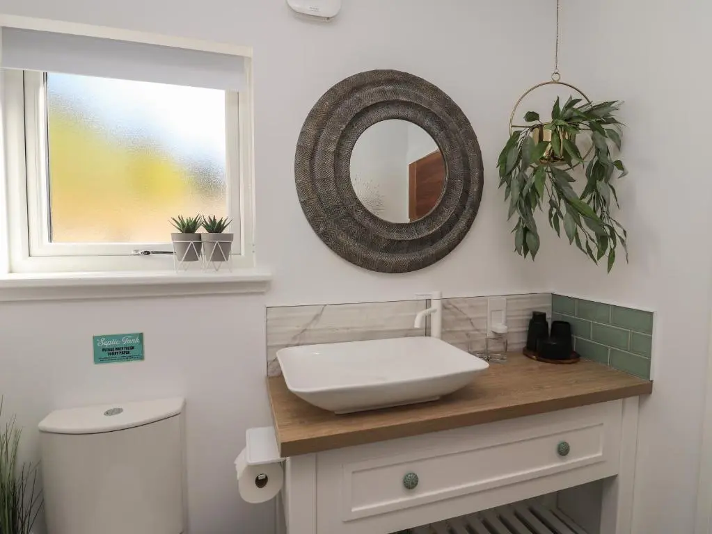 a bathroom with a sink and a mirror on a counter at Core-na-bye in Inverness