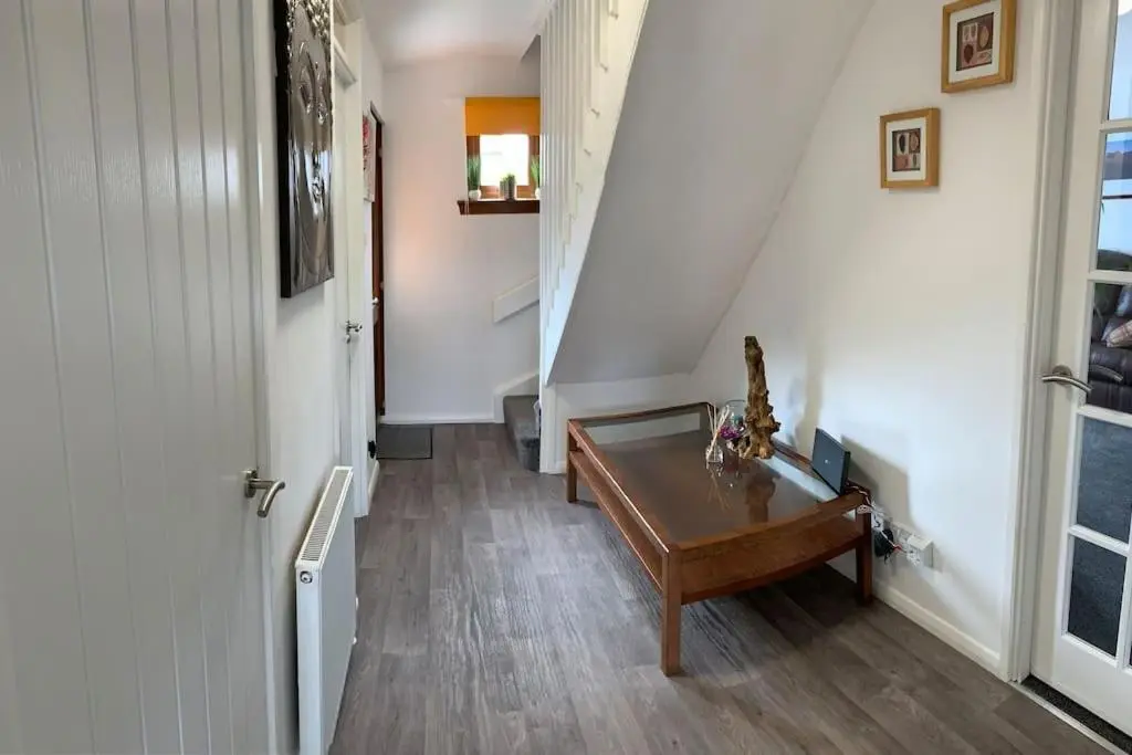 a hallway with a wooden table and a stair case at No.46, comfortable 2 bedroom property in Rothes