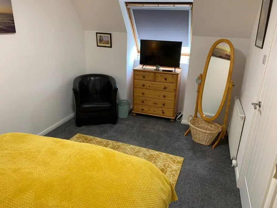 a bedroom with a bed and a mirror and a television at No.46, comfortable 2 bedroom property in Rothes