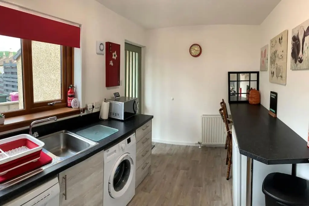 a kitchen with a sink and a washing machine at No.46, comfortable 2 bedroom property in Rothes