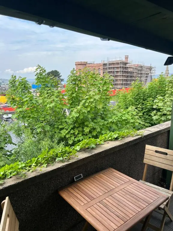 a wooden bench sitting on a balcony with plants at Floras View in Inverness