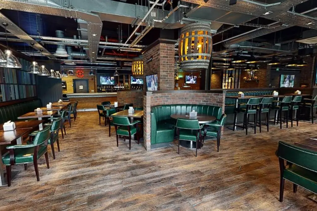 a restaurant with wooden tables and green chairs at Village Hotel Aberdeen in Aberdeen
