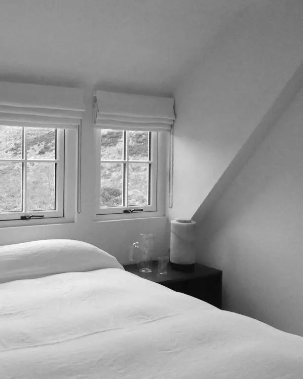 a bedroom with a white bed and two windows at Laggan Cottage - Charming home along River Gairn with unique panoramic room in Ballater