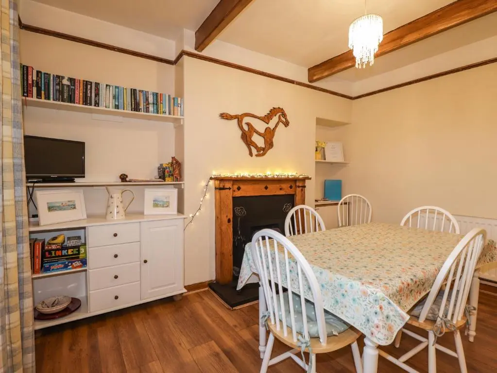 a dining room with a table and a fireplace at Rowan Tree House in Brora