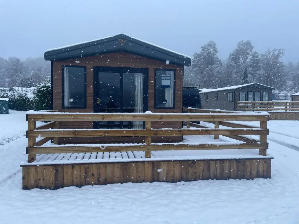 a building with a fence in the snow at The Drey in Grantown on Spey