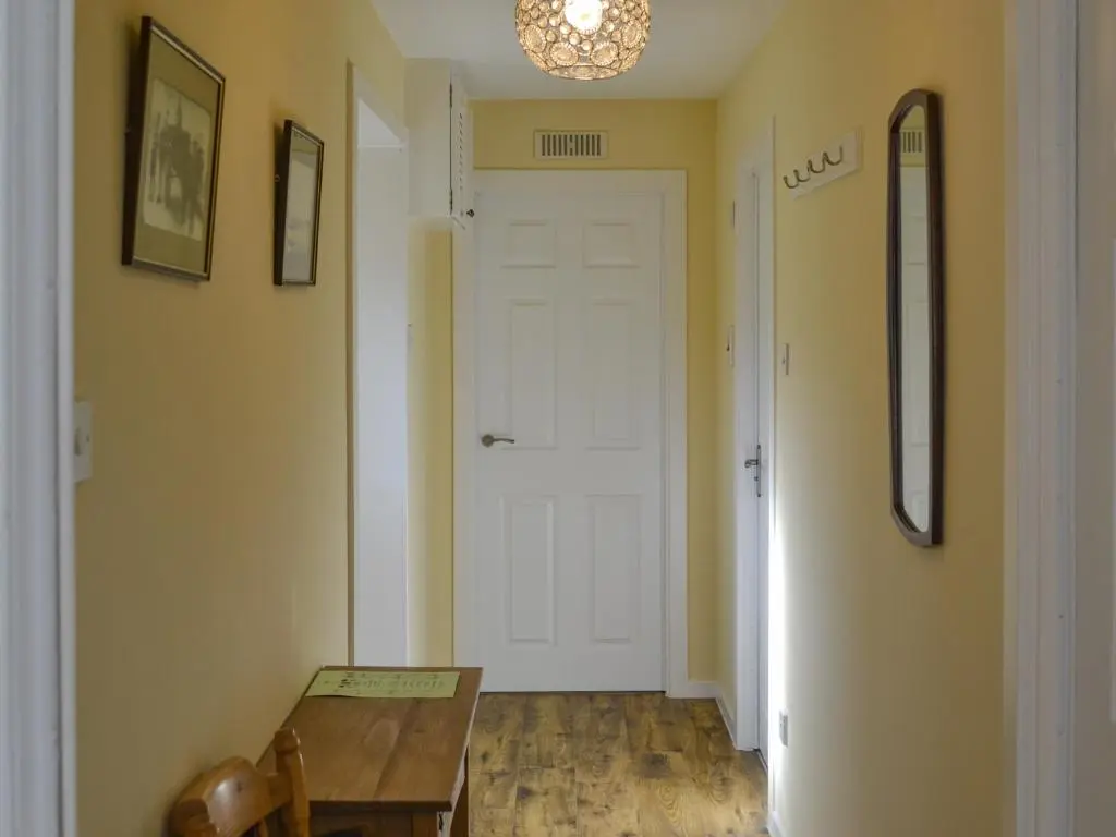 a hallway with a table and a white door at Sandy Bay in Portmahomack