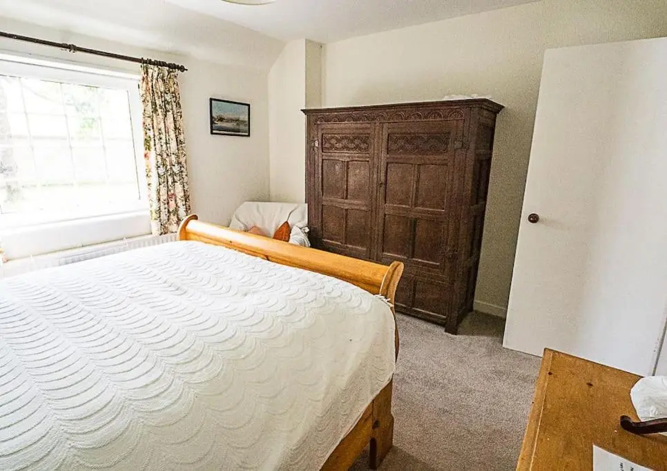 a bedroom with a bed and a wooden cabinet at West Lodge 3 bedrooms, near golf course and river in Turriff
