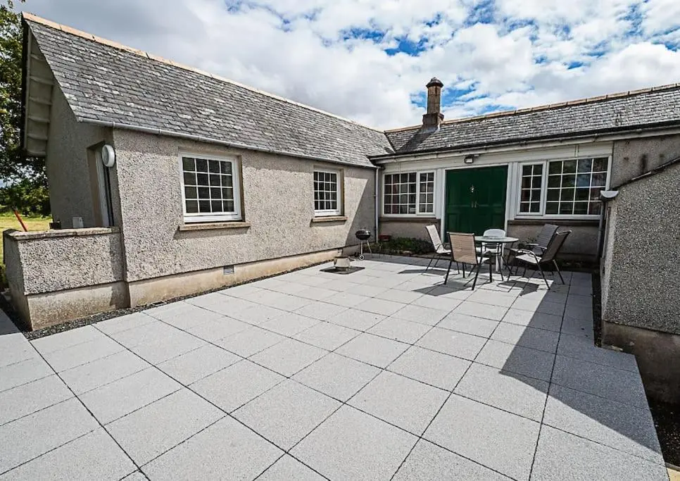 a patio with a table and chairs in front of a building at West Lodge 3 bedrooms, near golf course and river in Turriff
