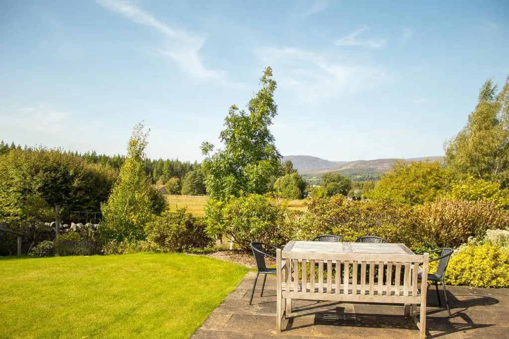 a patio with a table and chairs in a garden at Carriden in Insh