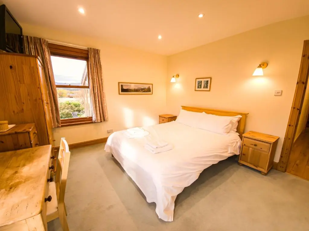 a bedroom with a white bed and a window at Carriden in Insh