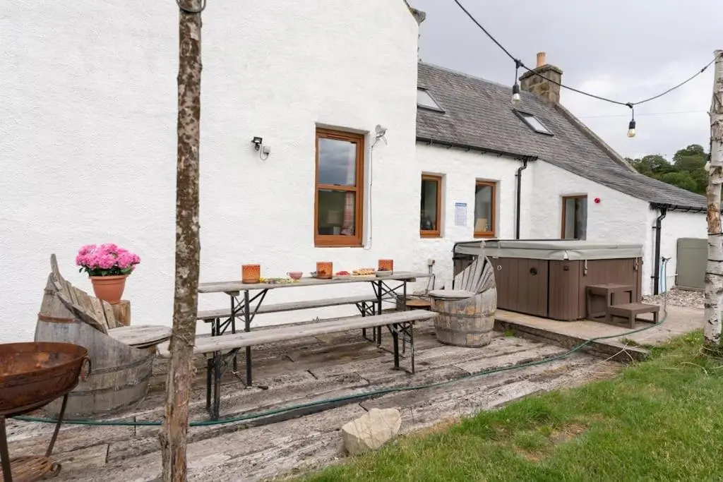 a patio with a table and a grill in front of a house at Jacobite Lodge by The House of Danu in Kingussie