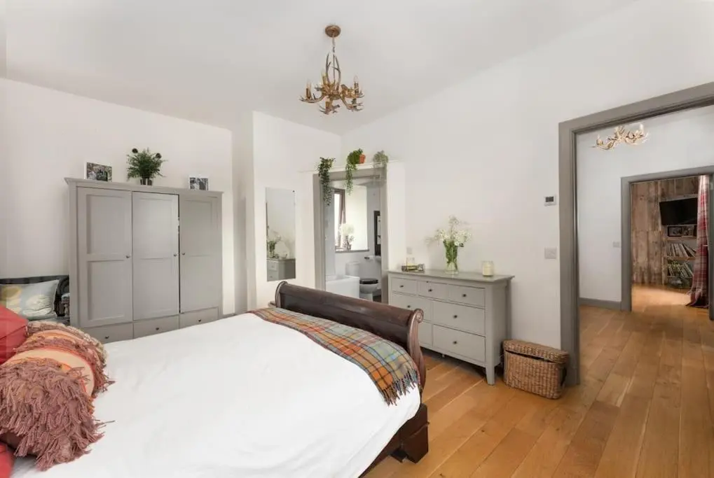 a bedroom with a white bed and a dresser at Jacobite Lodge by The House of Danu in Kingussie