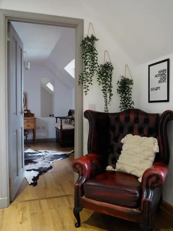 a leather couch in a living room with plants at Jacobite Lodge by The House of Danu in Kingussie