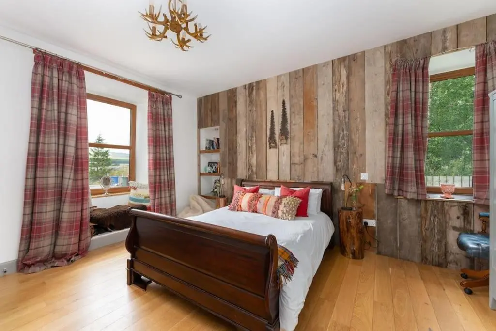 a bedroom with a bed with red pillows on it at Jacobite Lodge by The House of Danu in Kingussie