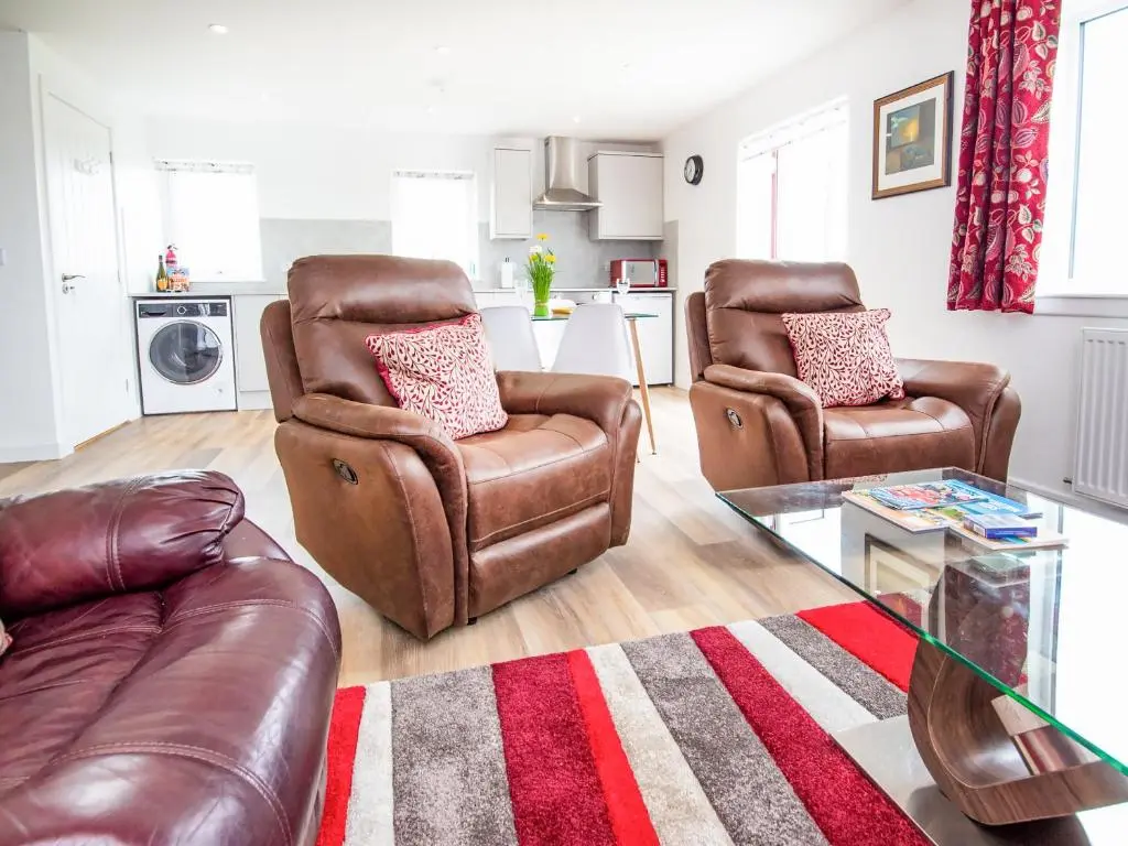 a living room with two leather chairs and a table at Cranberry Cottage in Wick
