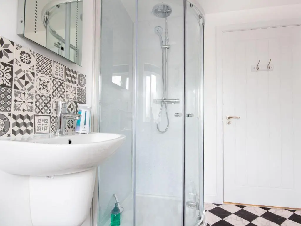 a white bathroom with a sink and a shower at Cranberry Cottage in Wick