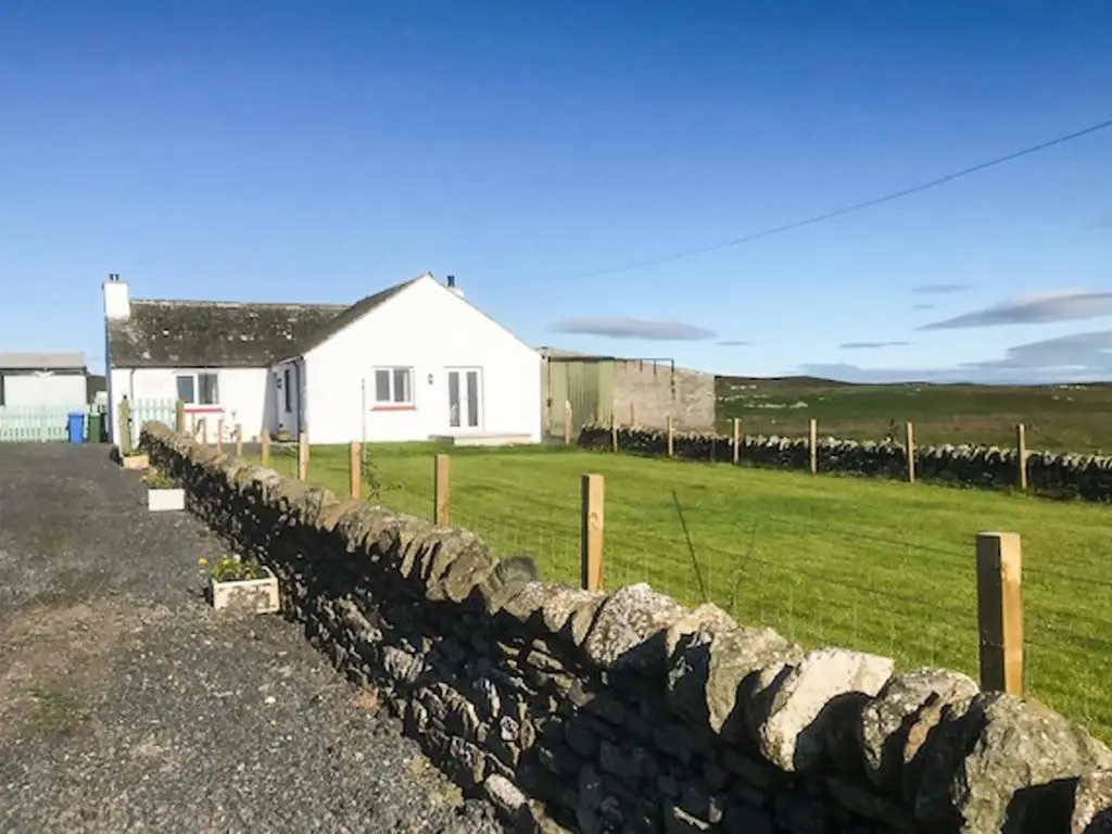 a stone fence in front of a white house at Cranberry Cottage in Wick