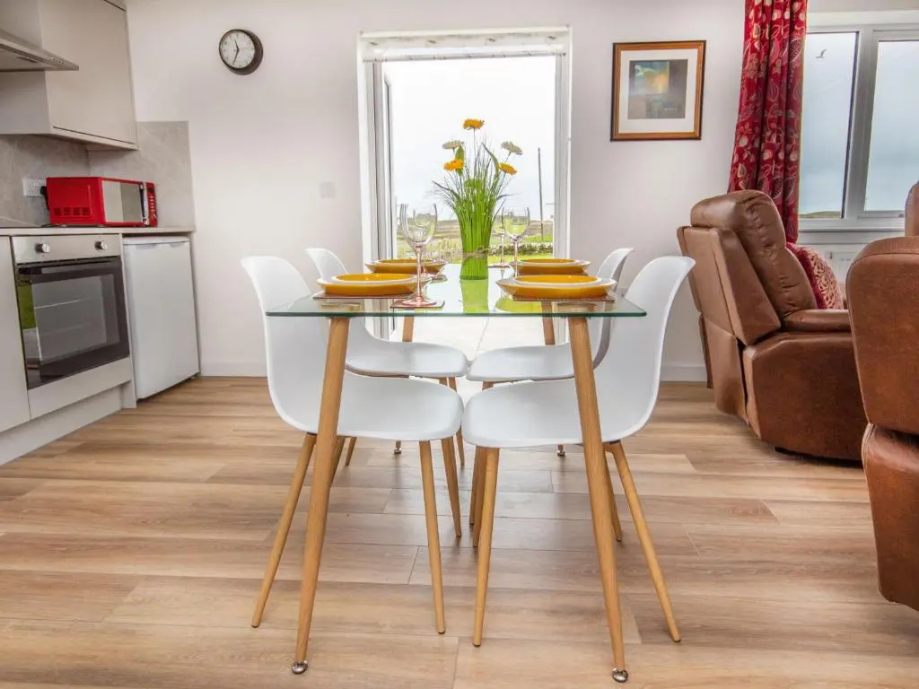 a dining room with a glass table and white chairs at Cranberry Cottage in Wick