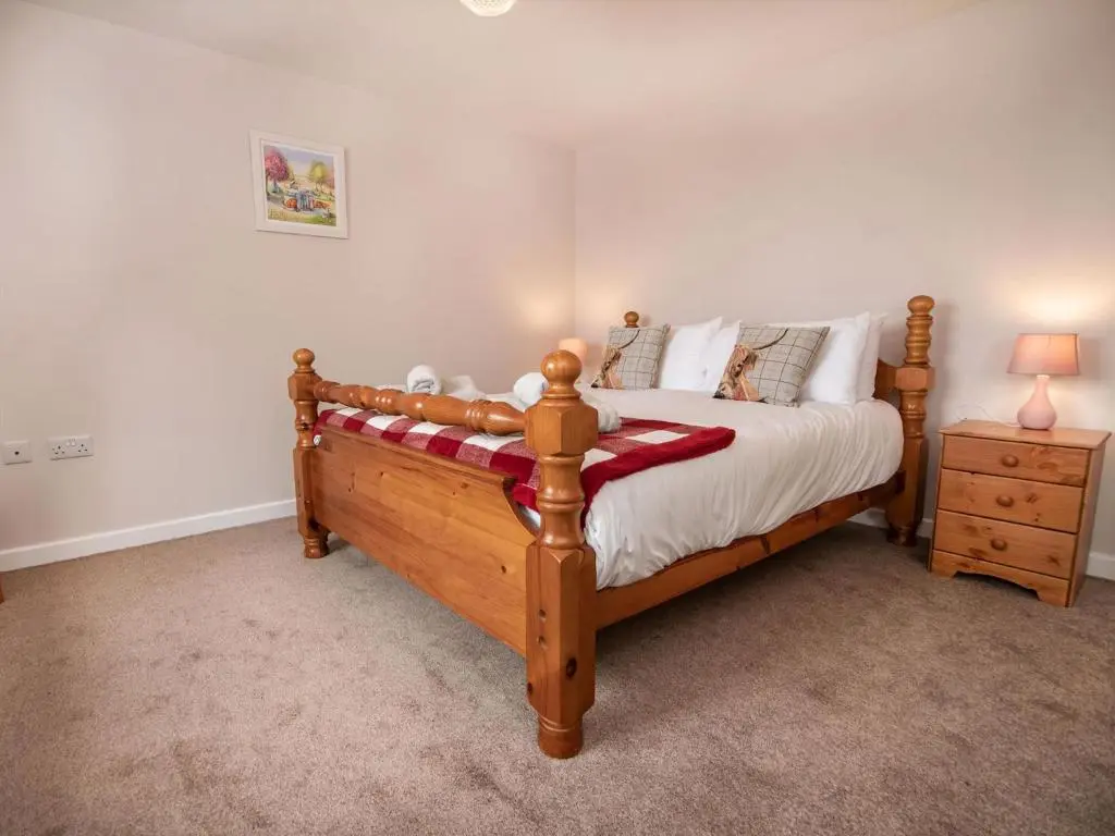 a bedroom with a wooden bed and a night stand at Cranberry Cottage in Wick