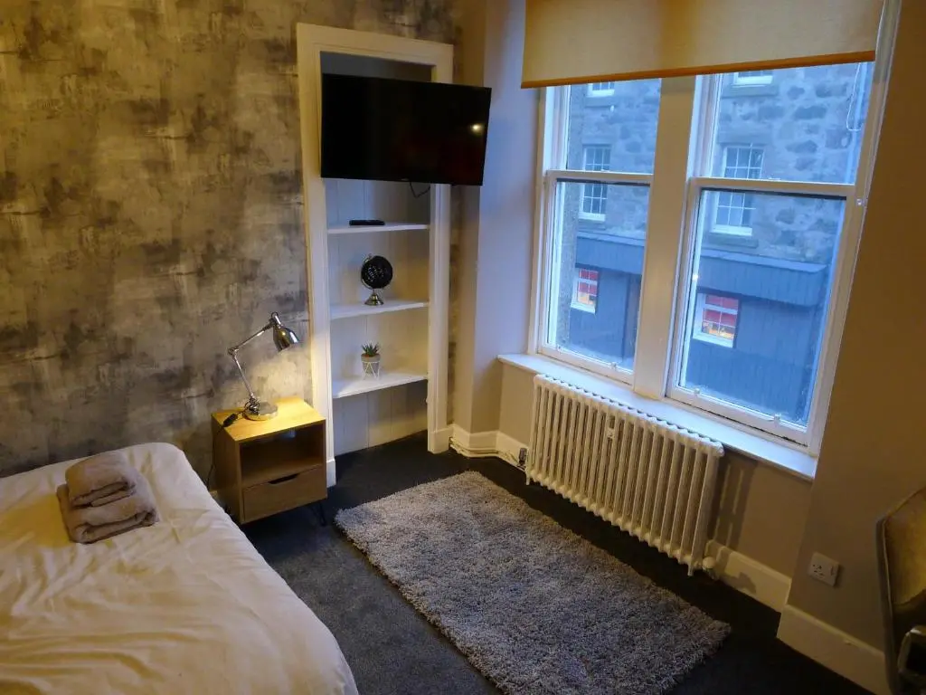 a bedroom with a bed and a tv and a window at Saltoun House in Fraserburgh